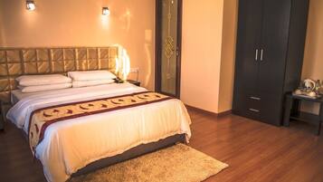 Une chambre à coucher comprenant un lit, une armoire, une table de chevet et une petite table avec une lampe.