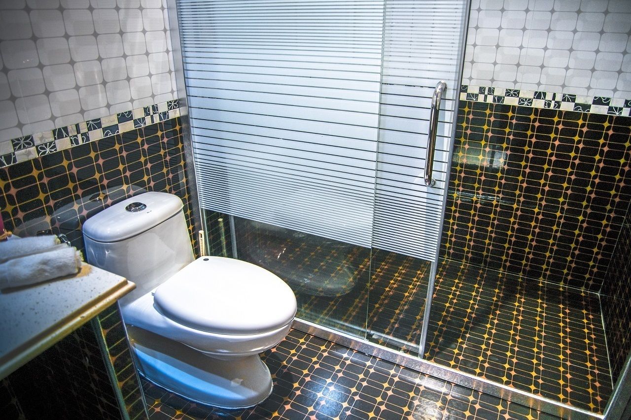 A bathroom with a toilet, a shower area, and a glass-enclosed shower stall.