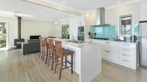 Een moderne keuken met een centraal eiland, inbouwapparatuur en een groot raam.