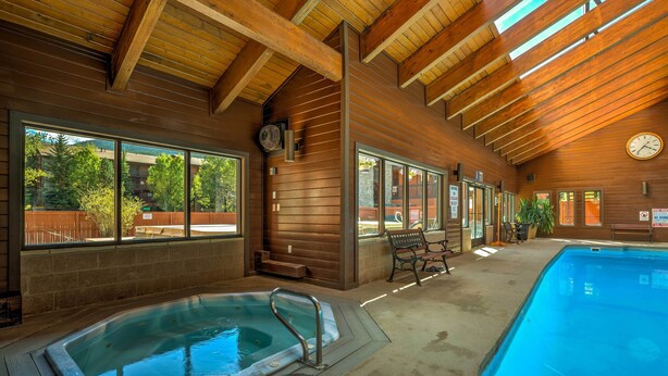 Una piscina interior con vigas de madera y ventanas amplias.