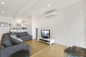 A modern living room with a grey sofa, a white entertainment unit, and a flat-screen TV. - Godalming (Lorne)