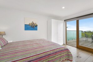 A bedroom with a bed, a painting, a wardrobe, and a balcony with a view. - Godalming (Lorne)