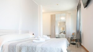 Una habitación de hotel con una cama grande, un escritorio con una silla y un espejo.