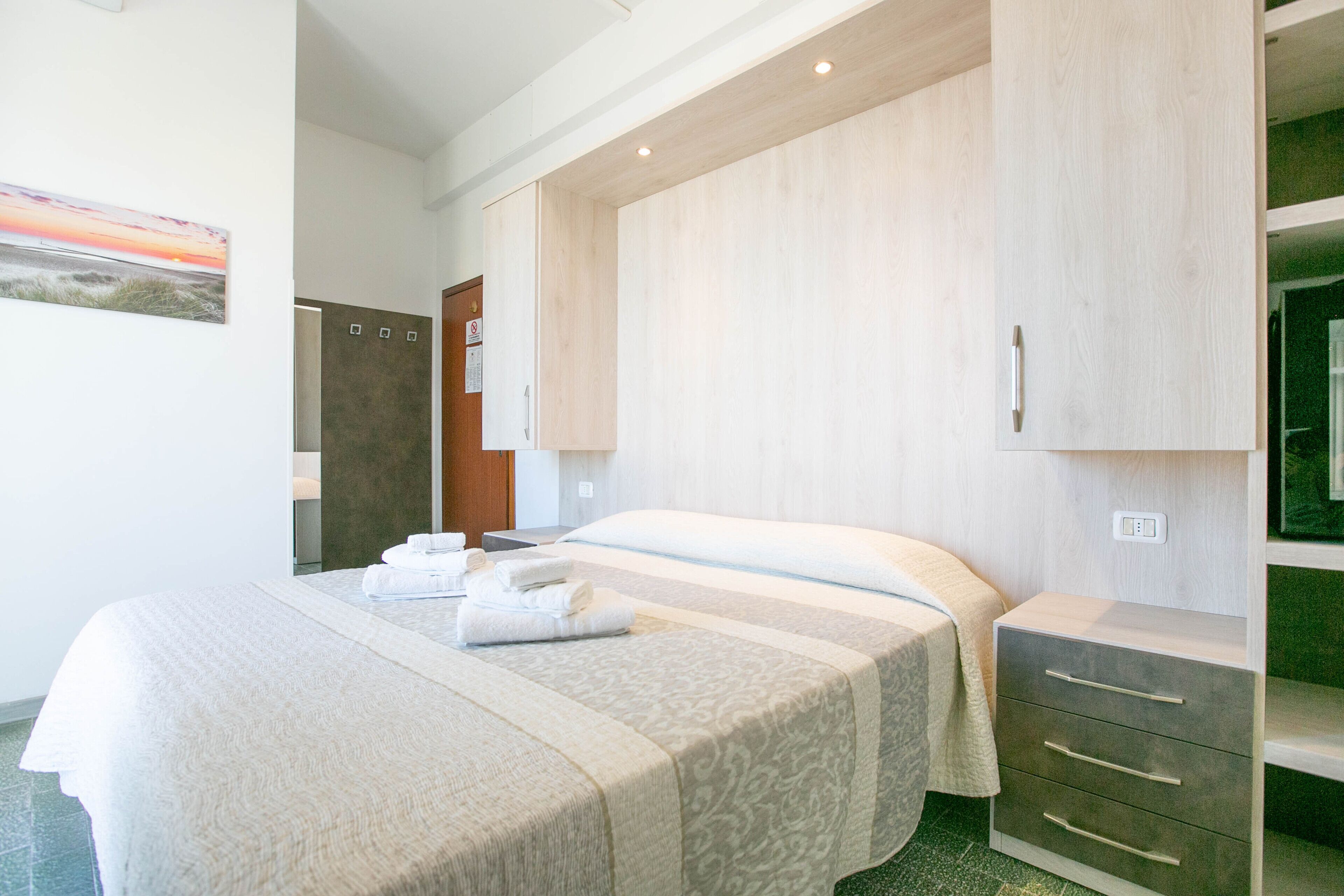 Una habitación de hotel con una cama grande, un armario y un baño a la vista a través de una puerta abierta.