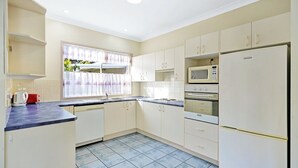 Una cocina compacta con gabinetes blancos, microondas, horno y refrigerador.