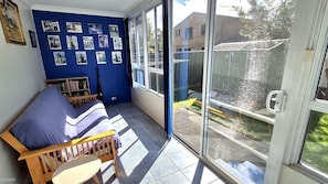 A room with a blue wall, a wooden bench, a small table, and a bookshelf.