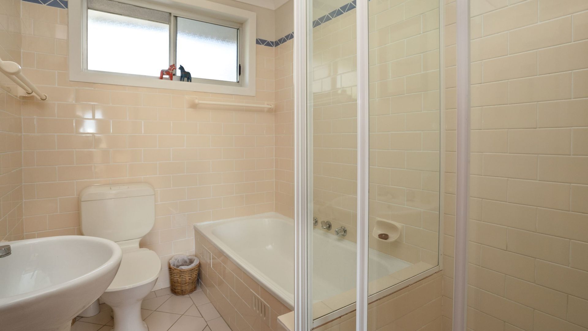 A bathroom with a toilet, bathtub, and a glass-enclosed shower area.