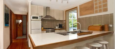 Una cocina moderna con una isla grande, electrodomésticos de acero inoxidable y vistas al exterior.