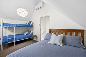 A bedroom with bunk beds, a single bed, a small table, and a hanging light fixture.