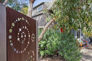 A garden area with a wooden fence featuring circular cutouts, a variety of green plants, and a bench.