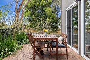 Eine Terrasse im Freien mit einem Holztisch, Stühlen, einer Bank und einem Blumentopf.