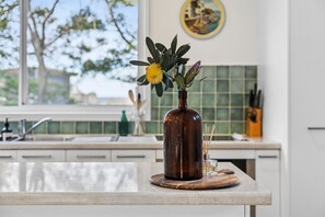 Eine Küchenarbeitsplatte mit einer braunen Vase, in der sich eine gelbe Blume und grüne Blätter befinden.