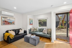 Ein Wohnzimmer mit zwei Sofas, einem Couchtisch und einem Fenster mit Blick ins Freie.