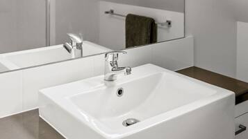 Une salle de bain moderne avec un grand miroir, deux vasques et des plantes vertes suspendues.