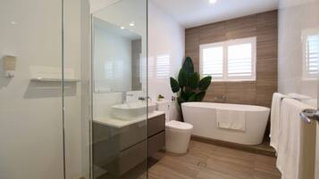 A modern bathroom with a glass shower enclosure, a freestanding bathtub, and a large mirror.
