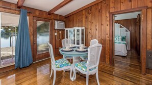 A wooden-paneled room with a dining table and chairs, a bed, and a view of a body of water. - 🌴 Charming 2BR WATERFRONT Cottage - Perfect for a Coastal Getaway! (Indian Rocks Beach)