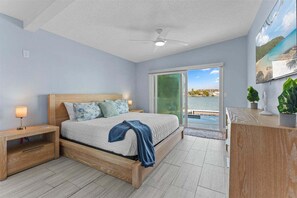 A bedroom with a bed, nightstands, a desk, and a view of the sea. - Water Lover's Paradise | Waterfront • Private Dock • Heated Pool (Indian Rocks Beach)