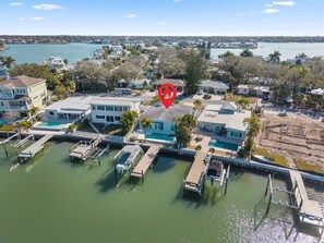 An aerial view of a marina with docked boats, waterfront houses, and a clear view of the water.