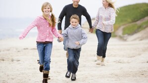 Een gezin wandelt over een zandstrand.