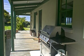 Ein Grillbereich im Freien mit einer Holzterrasse, einem Fenster und Blick auf die umliegende Natur.
