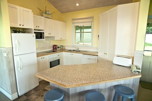 A kitchen with white cabinets, a granite countertop, a microwave, a stove, and a toaster.