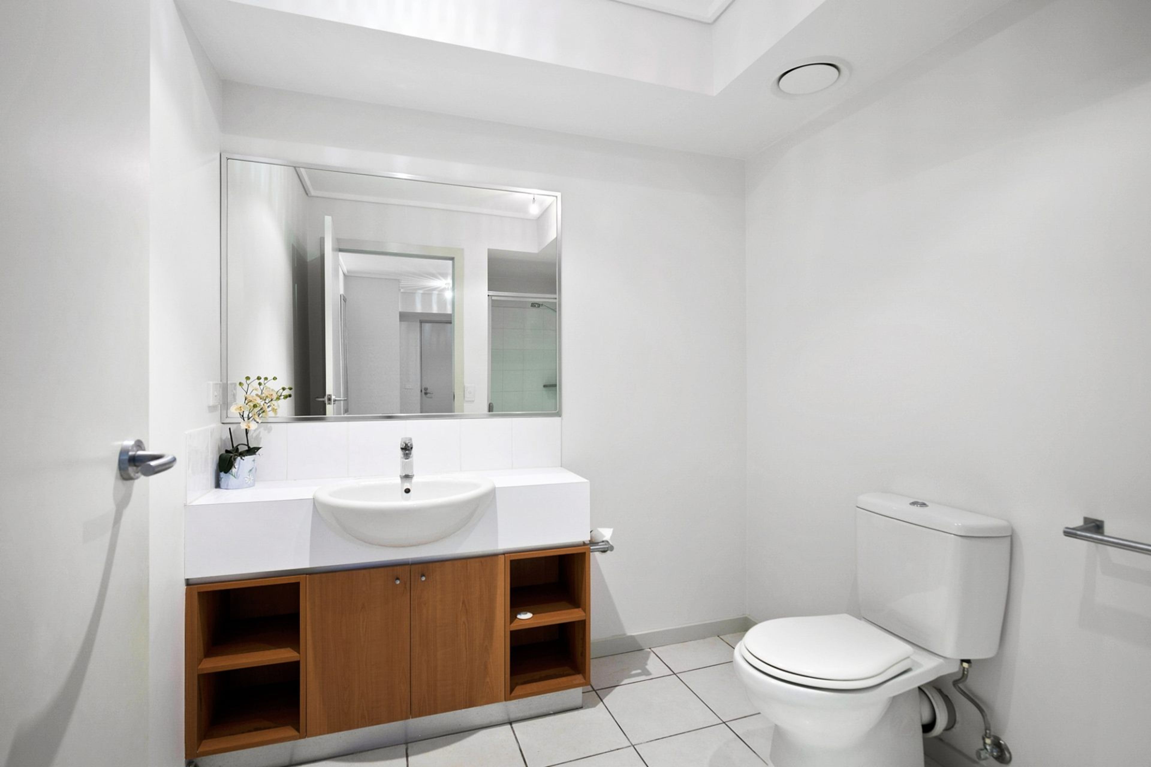 A modern bathroom with a white sink, mirror, and toilet.