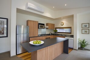 A modern kitchen with a built-in island, stainless steel appliances, wooden cabinets, and a microwave.