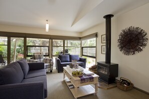 A cozy living room with a fireplace, comfortable seating, and large windows.