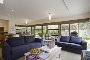 A modern living room with two sofas, a coffee table, and a dining area with chairs and a table.