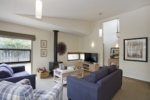 A modern living room with a fireplace, a television, and comfortable seating. - Purfect Purnell (Anglesea)