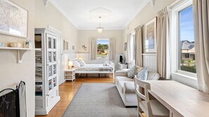 Un dormitorio con cama, mesitas de noche, un escritorio y una ventana con cortinas.