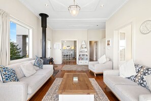 Amplia sala de estar con chimenea, sofás, una mesa de centro y una estantería.