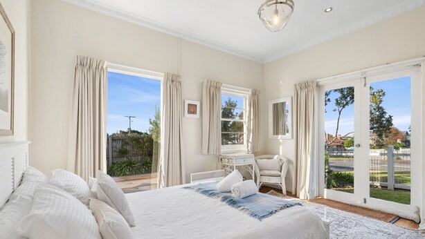 A bedroom with a large bed, a desk, and a chair, with a view of the outdoors through the windows. - The White House -Prime Location & Oozing Character (Apollo Bay)