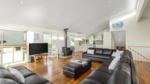 A modern living room with a large black sofa, a wooden coffee table, and a flat-screen TV on a stand.