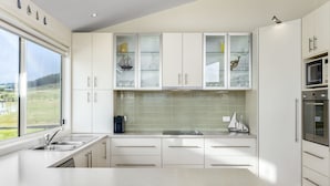 A modern kitchen with white cabinets, a large window, and a view of the outdoors.