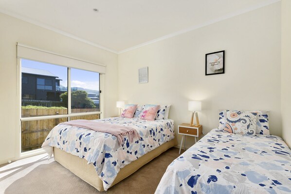 A bedroom with two beds, a window, and a wall-mounted picture.