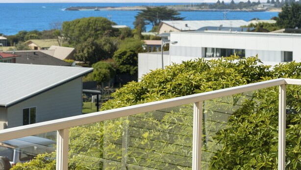 A residential area with a view of the sea, houses, and a white building with a balcony.
