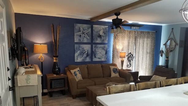 A living room with a brown sofa, a white table, and artwork on the walls.