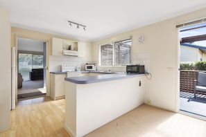 A compact kitchen with a built-in microwave, a stove, and a sink. - Budget By The Bay (Apollo Bay)
