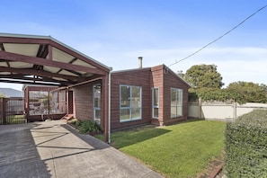 A residential property with a covered patio, a fenced yard, and a well-maintained lawn. - Budget By The Bay (Apollo Bay)