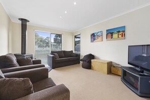 A living room with a fireplace, a sofa set, a television, and artwork on the wall. - Budget By The Bay (Apollo Bay)
