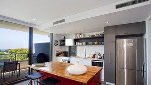 Una cocina moderna con una isla central, electrodomésticos de acero inoxidable y vistas al exterior.