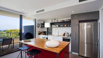 A modern kitchen with a central island, stainless steel appliances, and a view to the outside.