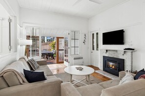 Ein Wohnzimmer mit Kamin, einem darüber montierten Fernseher und einer Couch mit Kissen.