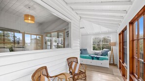 A room with a bed, two wicker chairs, a floor lamp, and large windows. - Sur La Mer (Lorne)