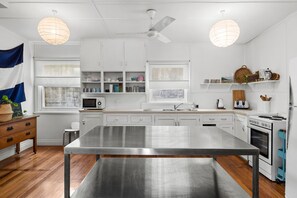 A modern kitchen with white cabinetry, a stainless steel island, and a built-in oven.