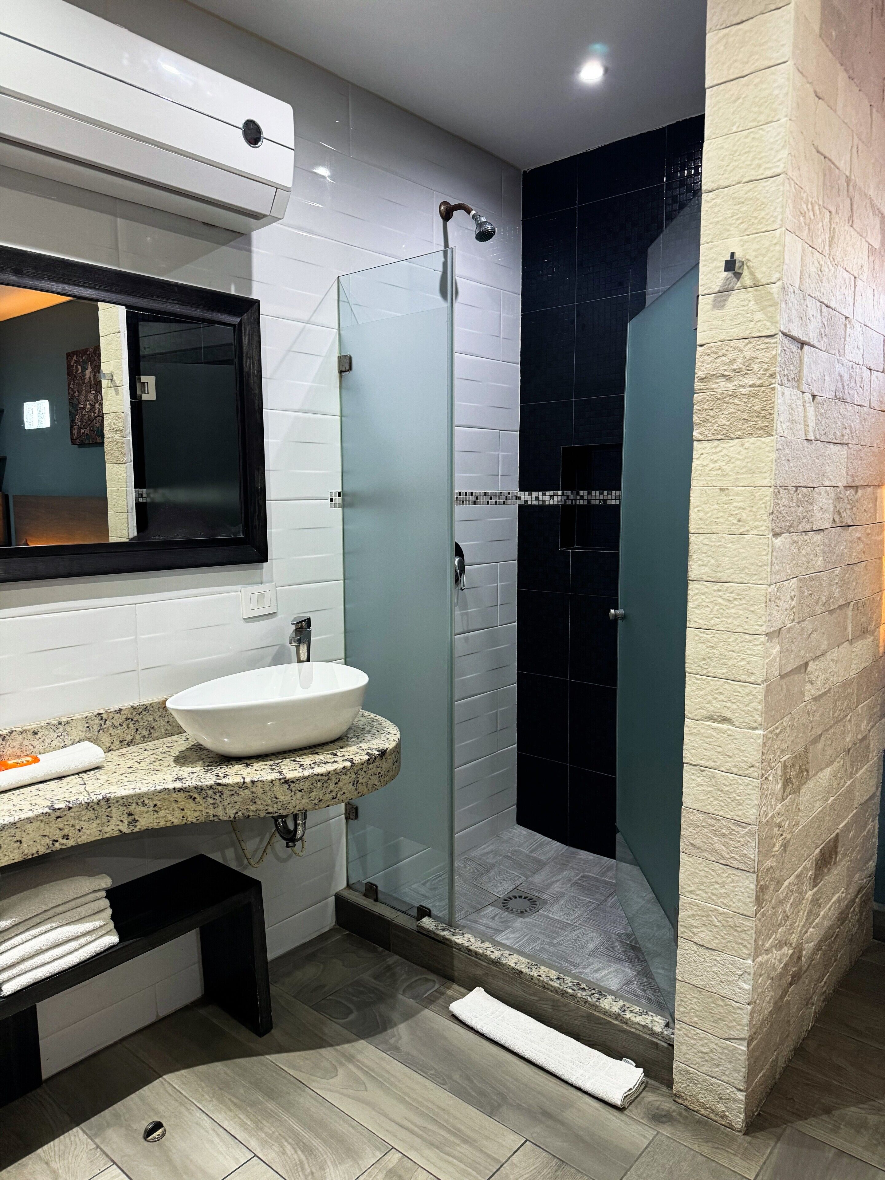 Une salle de bain moderne avec une douche à parois de verre, un lavabo blanc et un miroir au-dessus du plan de travail.