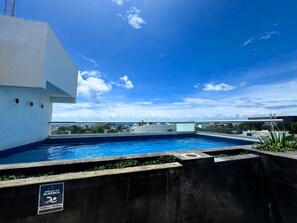 Een buitenzwembad, ligstoelen bij het zwembad