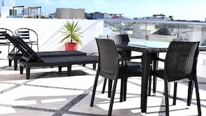 A rooftop terrace with a table and chairs, a potted plant, and a view of the city skyline. - ILLUSION XPRESS Downtown Playa (Playa del Carmen)