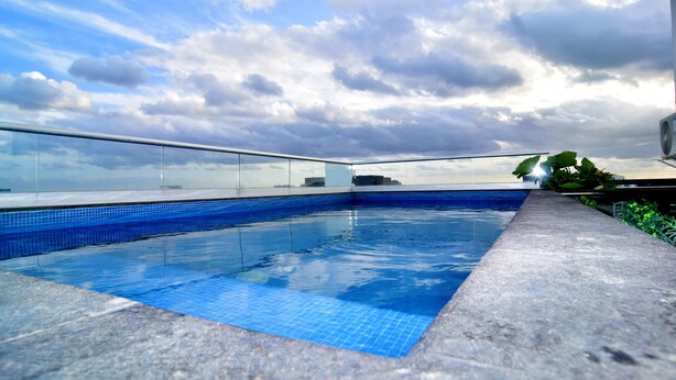 A rooftop swimming pool with a clear view of the sky and distant buildings. - ILLUSION XPRESS Downtown Playa (Playa del Carmen)